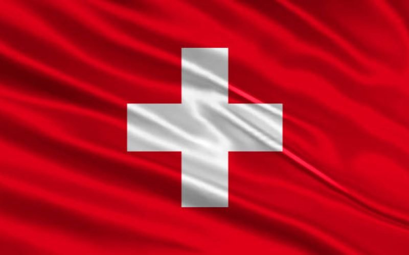 Switzerland flag design. Waving Swiss flag made of satin or silk fabric. Vector Illustration.